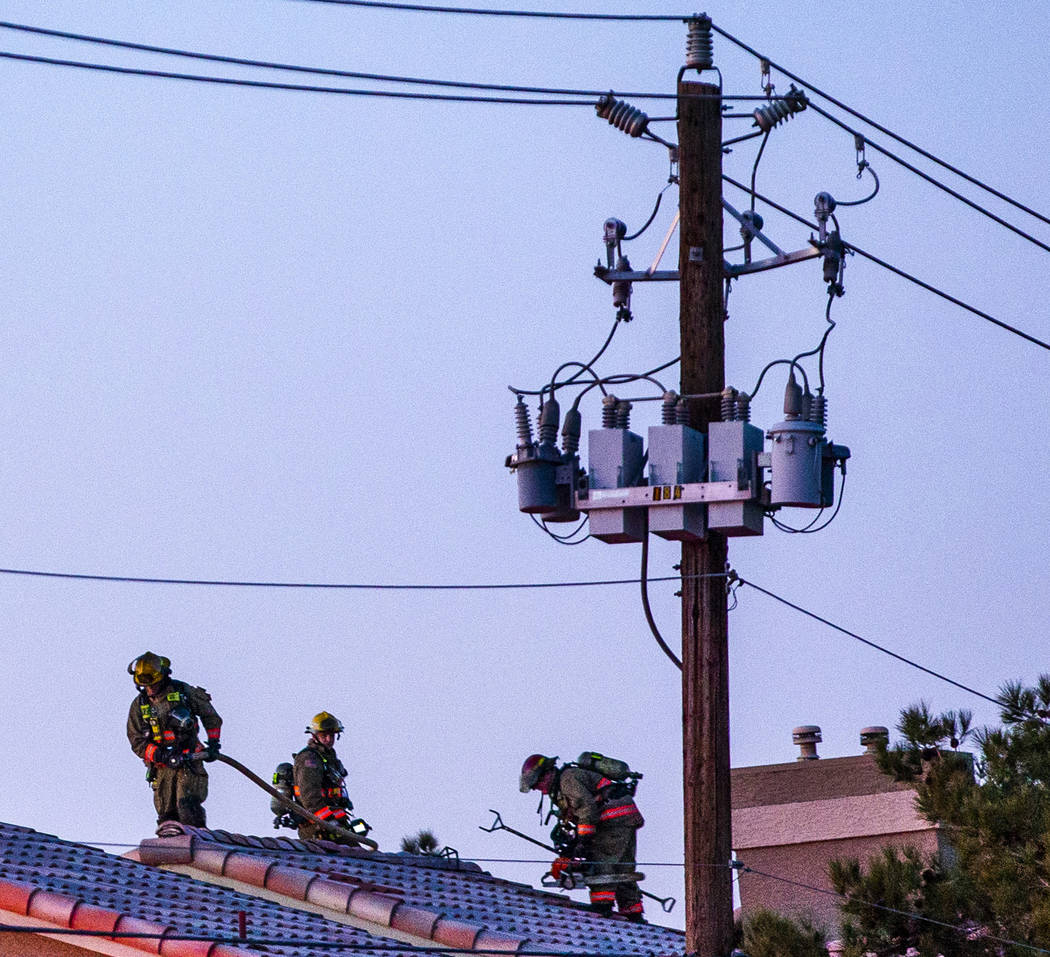 Firefighters with the Clark County Fire Department hose down the roof of an apartment at the Gl ...
