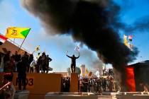 Protesters burn property in front of the U.S. embassy compound, in Baghdad, Iraq, Tuesday, Dec. ...