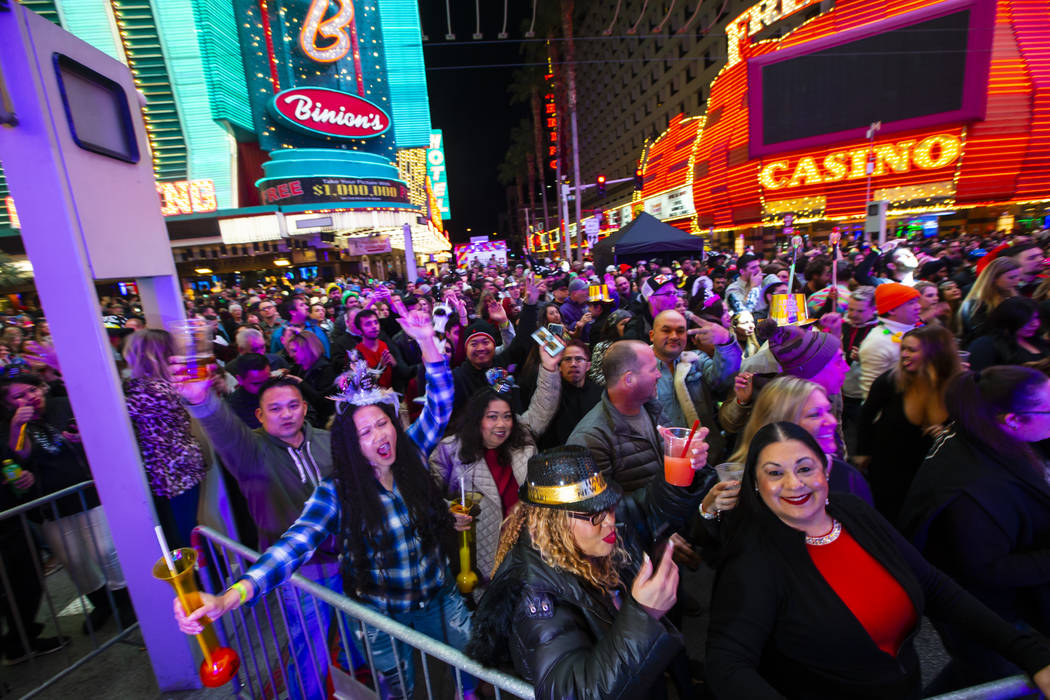 New Year’s Eve revelers dance by a stage at the Fremont Street