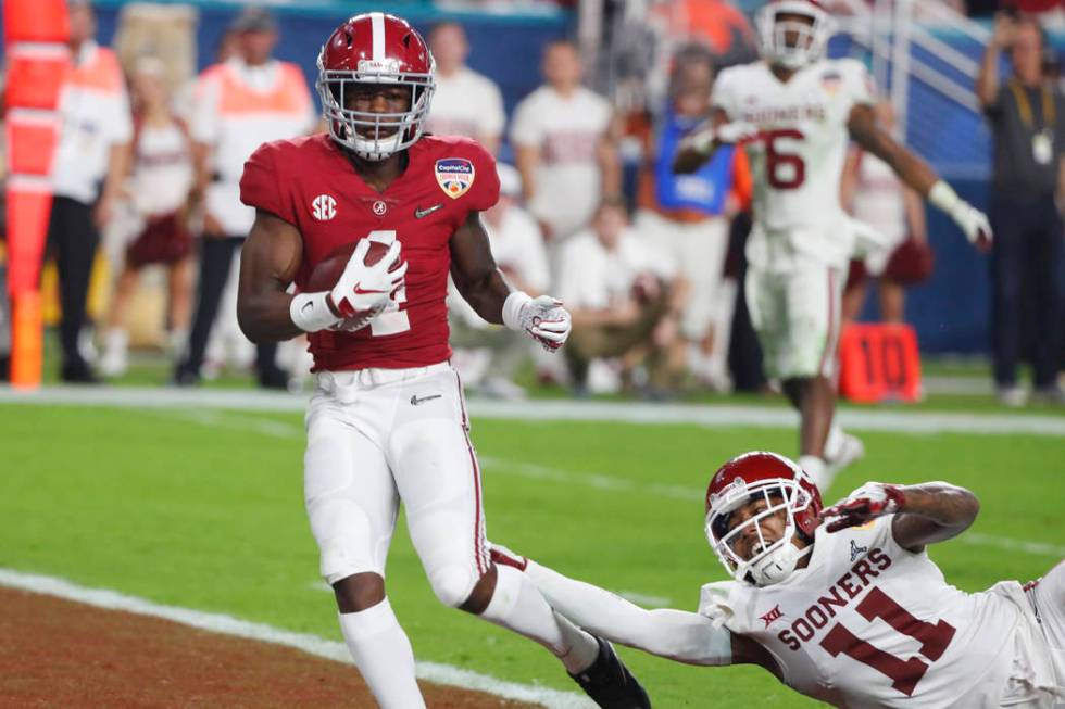 Alabama wide receiver Jerry Jeudy (4) scores a touchdown ahead of a takle by Oklahoma cornerbac ...