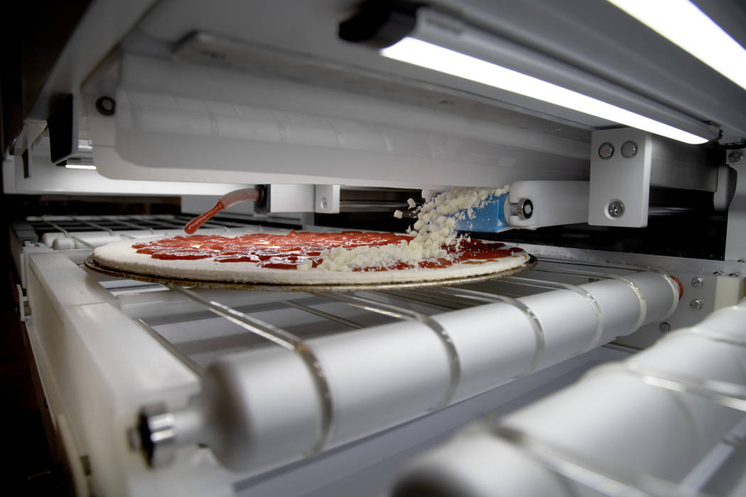 Cheese and sauce are added to the pizza robotically. (Picnic)