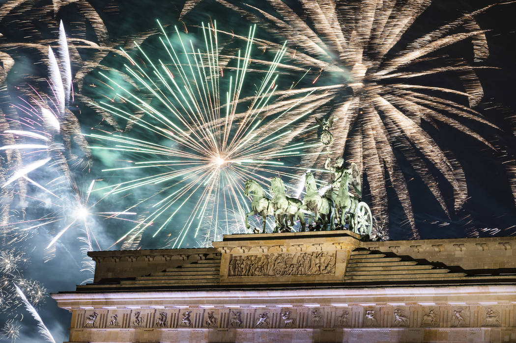 Fireworks light the sky above the Quadriga at the Brandenburg Gate during New Year celebrations ...