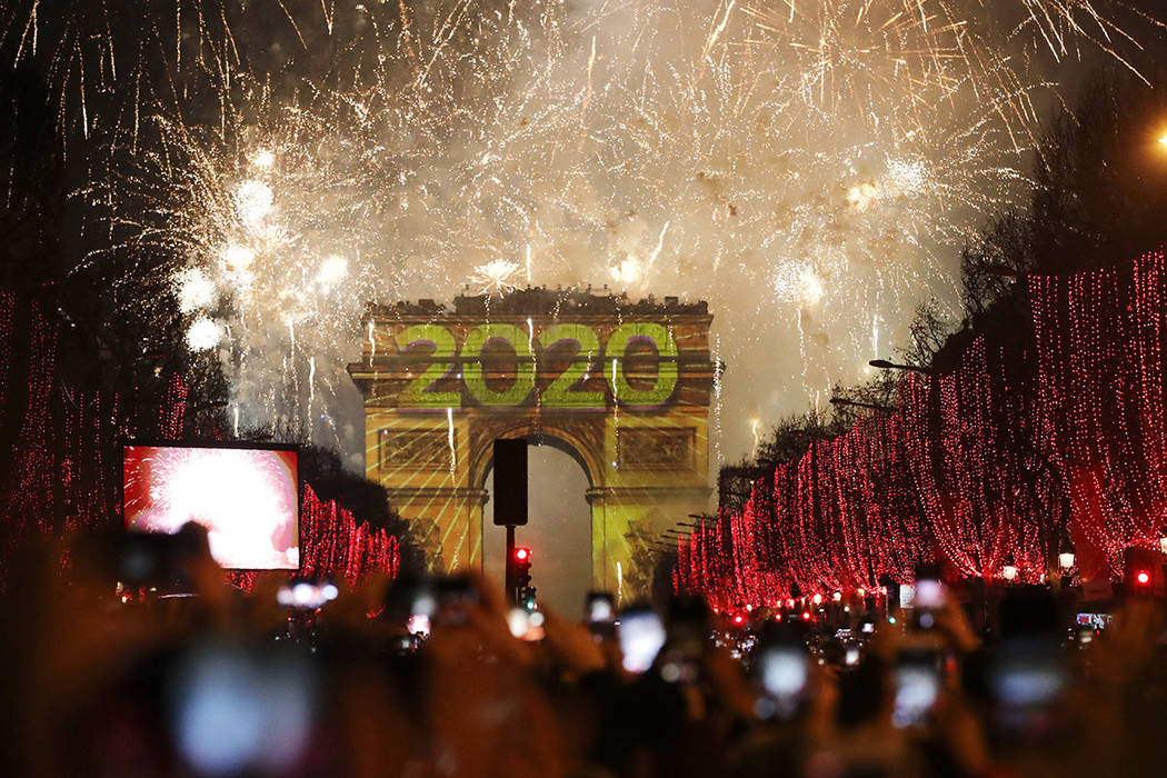 Revellers photograph fireworks over the Arc de Triomphe as they celebrate the New Year on the C ...