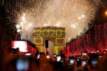 Revellers photograph fireworks over the Arc de Triomphe as they celebrate the New Year on the C ...