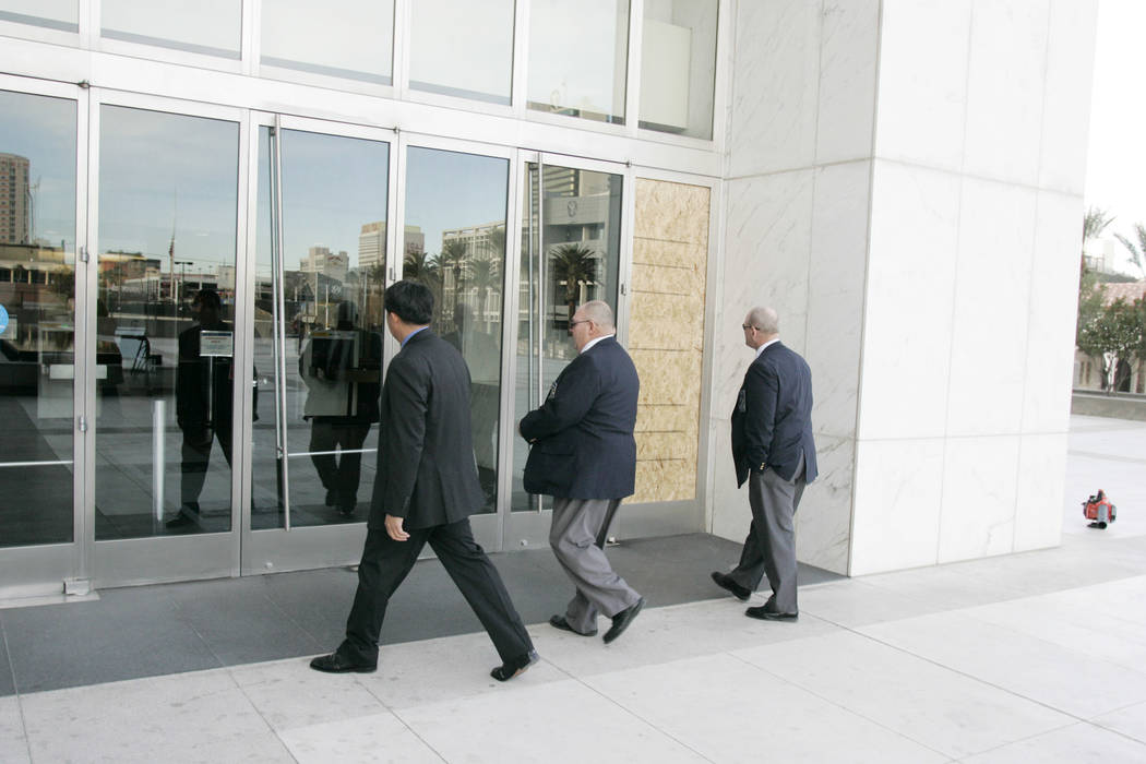 Three men approach the Lloyd George U.S. Courthouse past a wood panel replacing a window that w ...