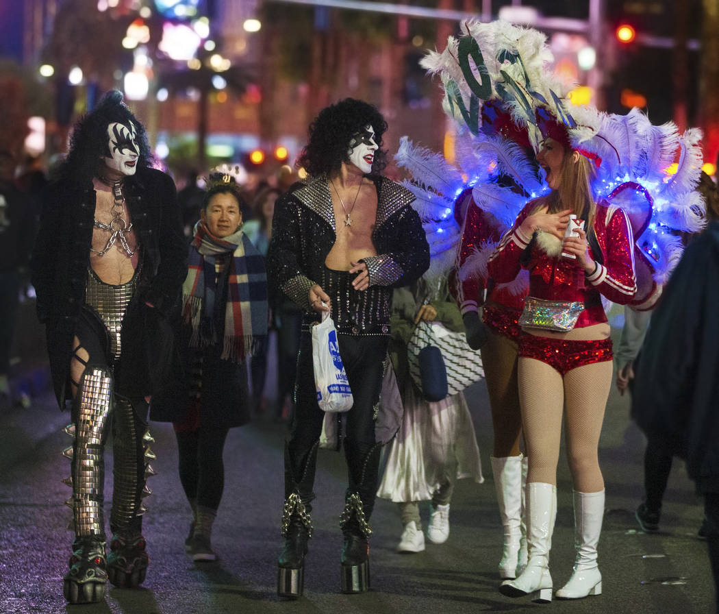 Showgirls, right, share a moment with street performers dressed in Kiss attire on the Strip on ...