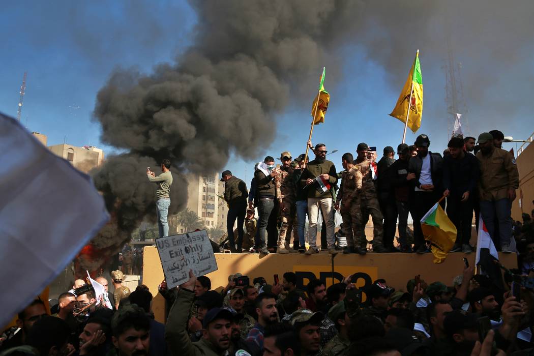 Protesters burn property in front of the U.S. embassy compound, in Baghdad, Iraq, Tuesday, Dec. ...