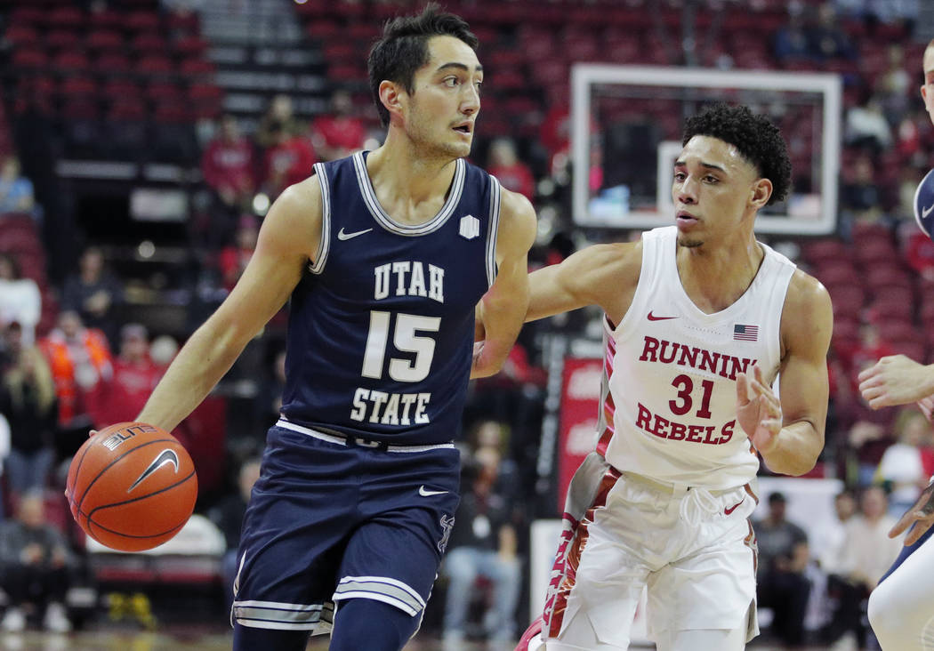 Utah State's Abel Porter (15) drives around UNLV's Marvin Coleman (31) during the first half of ...