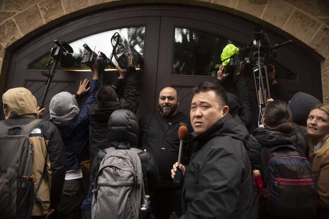 A private security guard, center, stands as journalists film through the garage window of the h ...
