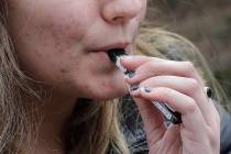 In an April 11, 2018, file photo, a high school student uses a vaping device near a school camp ...