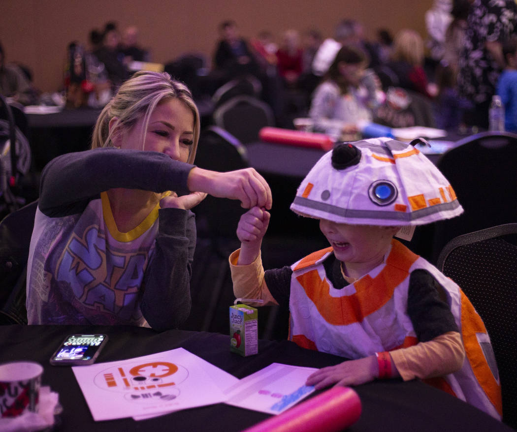 Jaxson Evans grabs a crayon from his mom, Melissa Evans, to color his light saber handle at the ...