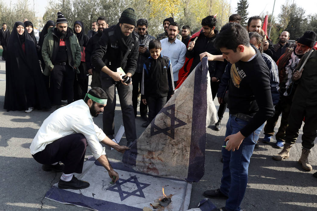 Protesters burn representations of Israeli flag during a demonstration over the U.S. airstrike ...
