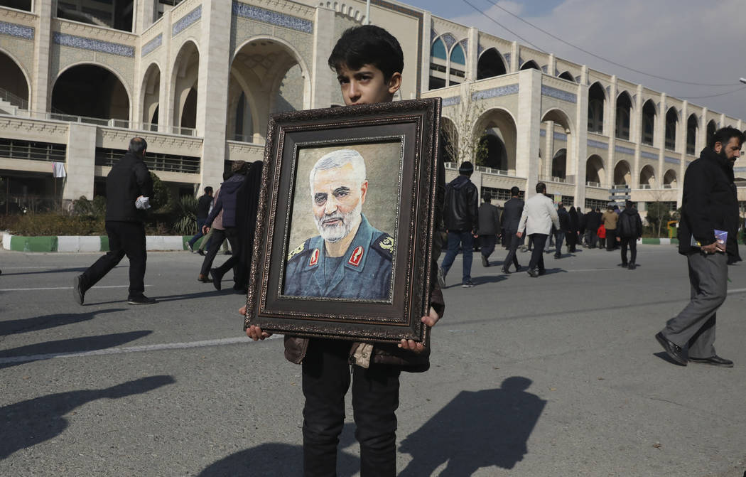 A boy carries a portrait of Iranian Revolutionary Guard Gen. Qassem Soleimani, who was killed i ...