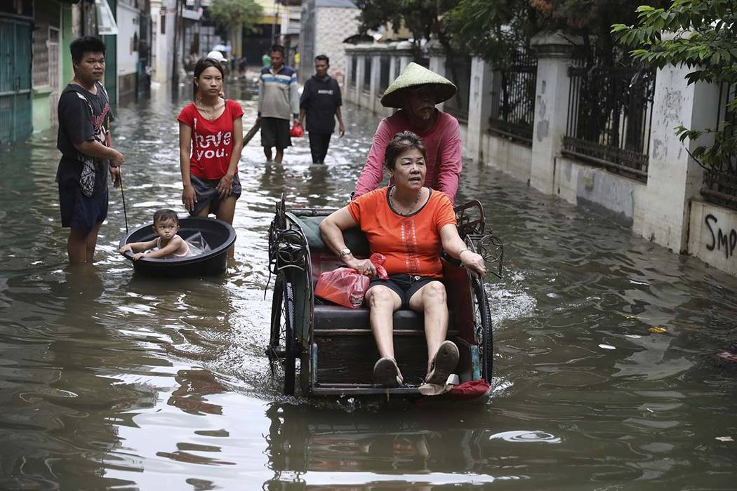 A woman rides a tricycle on a flooded street in Jakarta, Indonesia, Saturday, Jan. 4, 2020. Mon ...