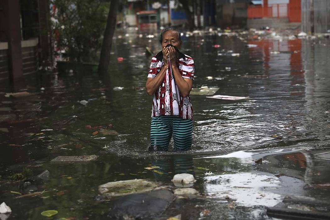 A woman reacts as she wades flood water in Jakarta, Indonesia, Saturday, Jan. 4, 2020. Monsoon ...