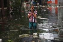 A woman reacts as she wades flood water in Jakarta, Indonesia, Saturday, Jan. 4, 2020. Monsoon ...