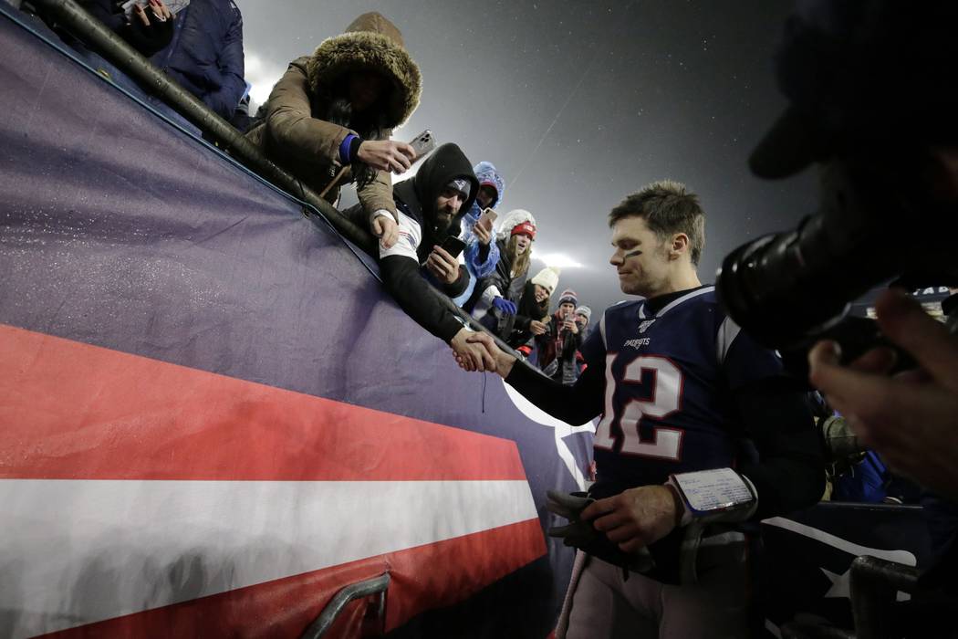 New England Patriots quarterback Tom Brady shakes hands with a fan as he leaves the field after ...