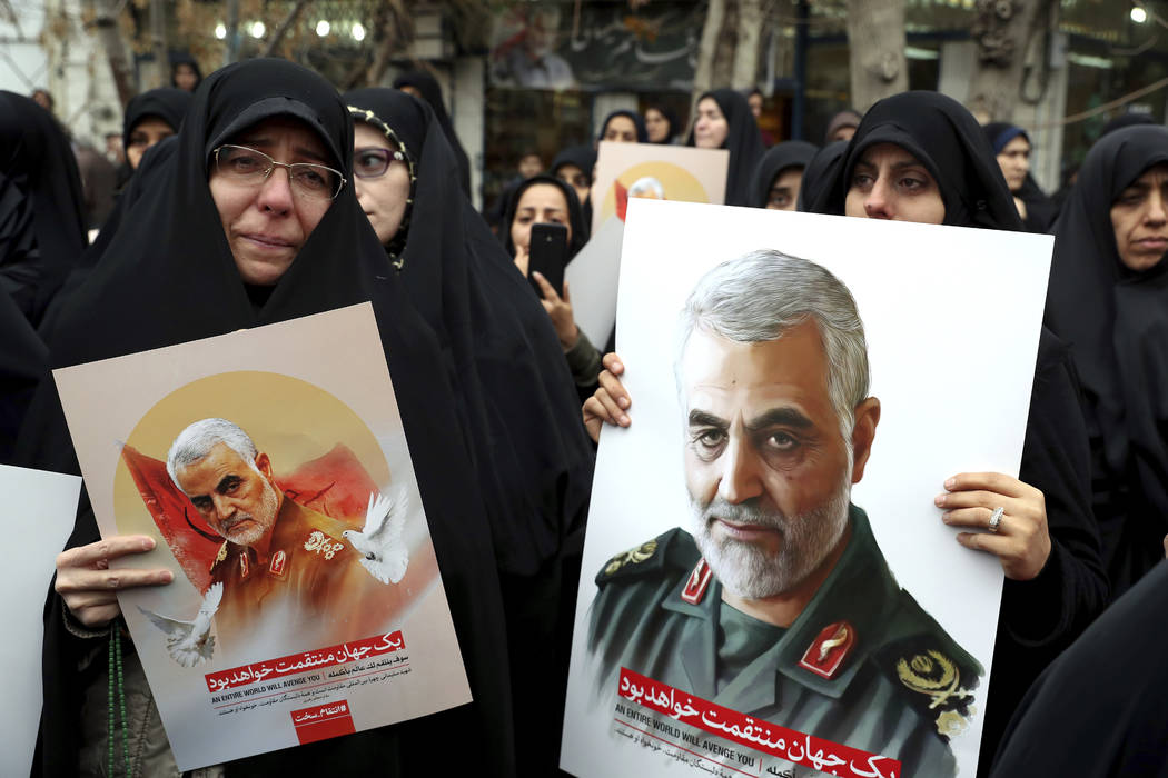 Protesters hold up posters of Gen. Qassem Soleimani while mourning during a demonstration over ...