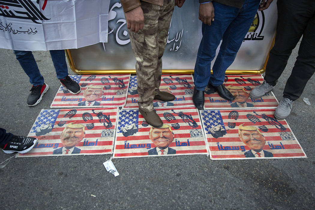 Mourners step over a U.S. flags with pictures of President Trump while waiting for the funeral ...