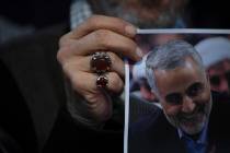 A supporter of Hezbollah leader Sayyed Hassan Nasrallah holds a portrait of killed Iranian Revo ...