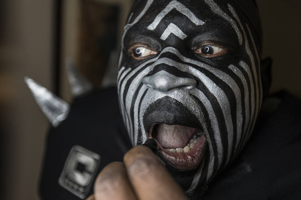 Raiders super fan Wayne Mabry, known as "Violator," applies makeup in his hotel room ...