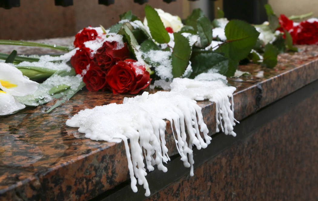 Wax from melted candles next to flowers are placed at the Canadian Embassy during a national da ...
