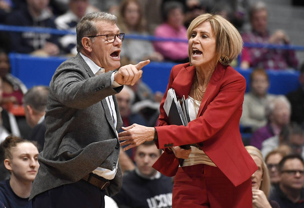 Connecticut coach Geno Auriemma, left, is held back by associate head coach Chris Dailey, right ...