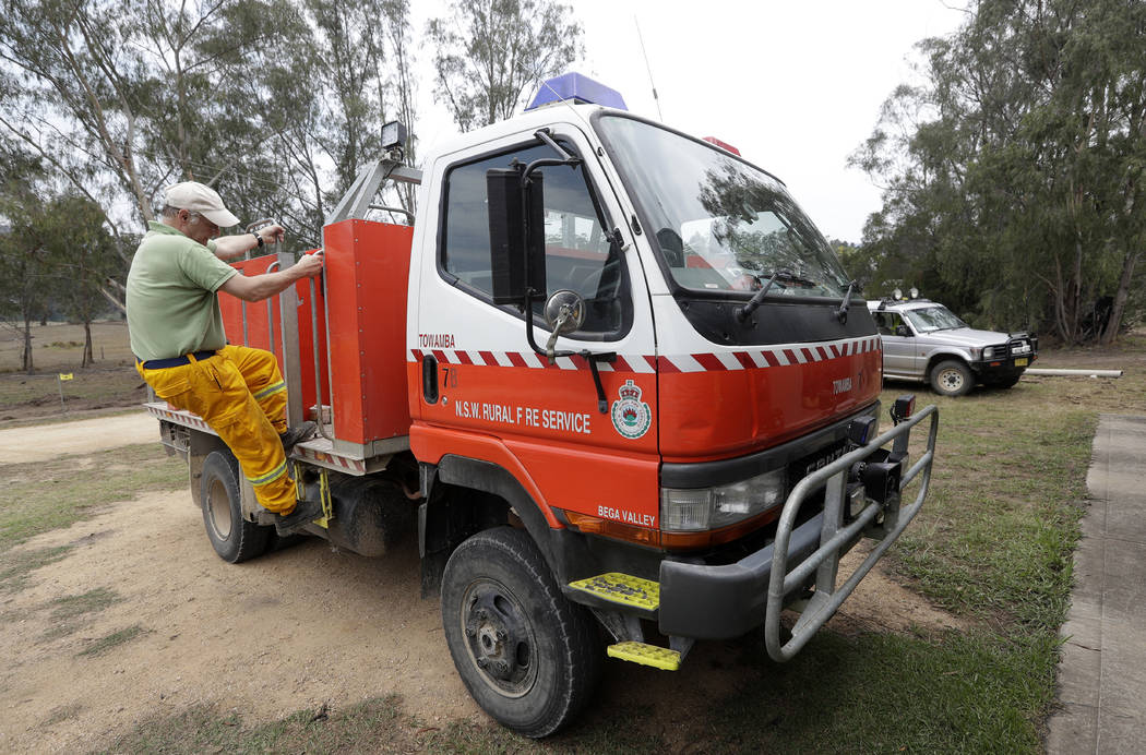 A volunteer firefighter prepares a truck as they plan their defense against the fire near Towam ...
