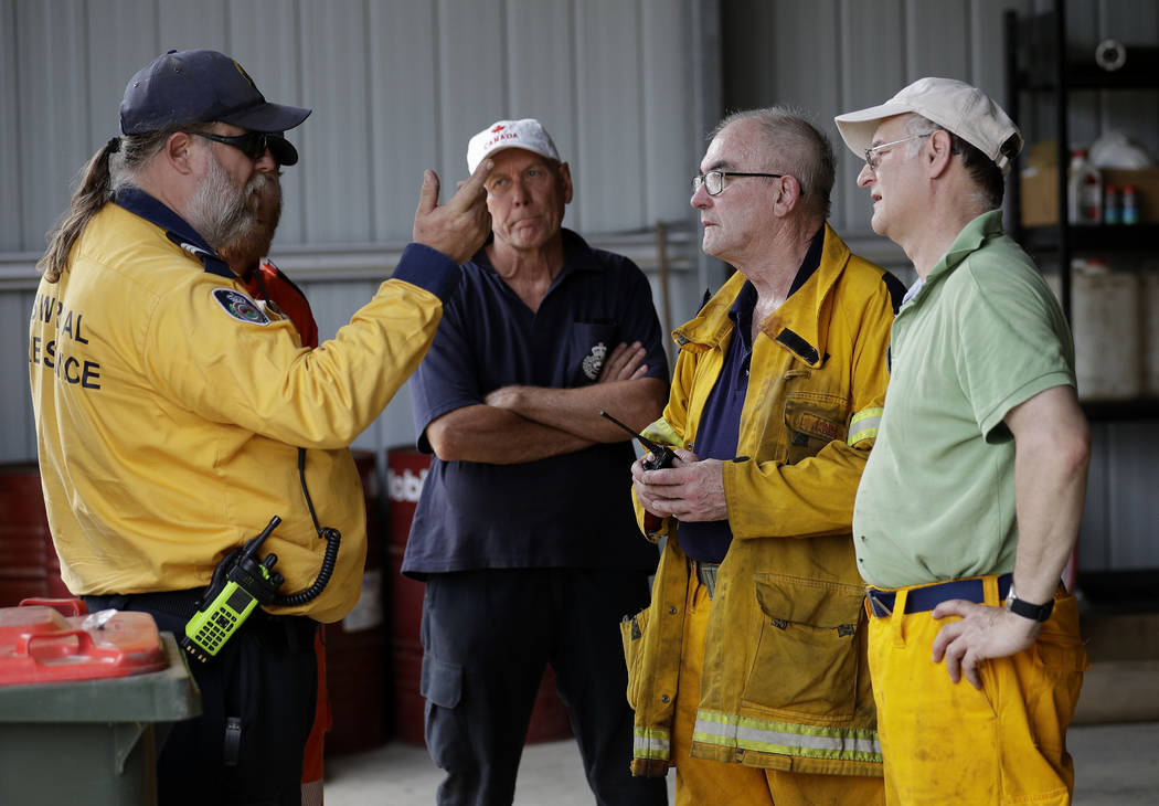 Volunteer firefighters discuss their planned defense against the fire near Towamba, Australia, ...
