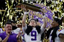 LSU quarterback Joe Burrow holds the trophy as safety Grant Delpit looks on after a NCAA Colleg ...