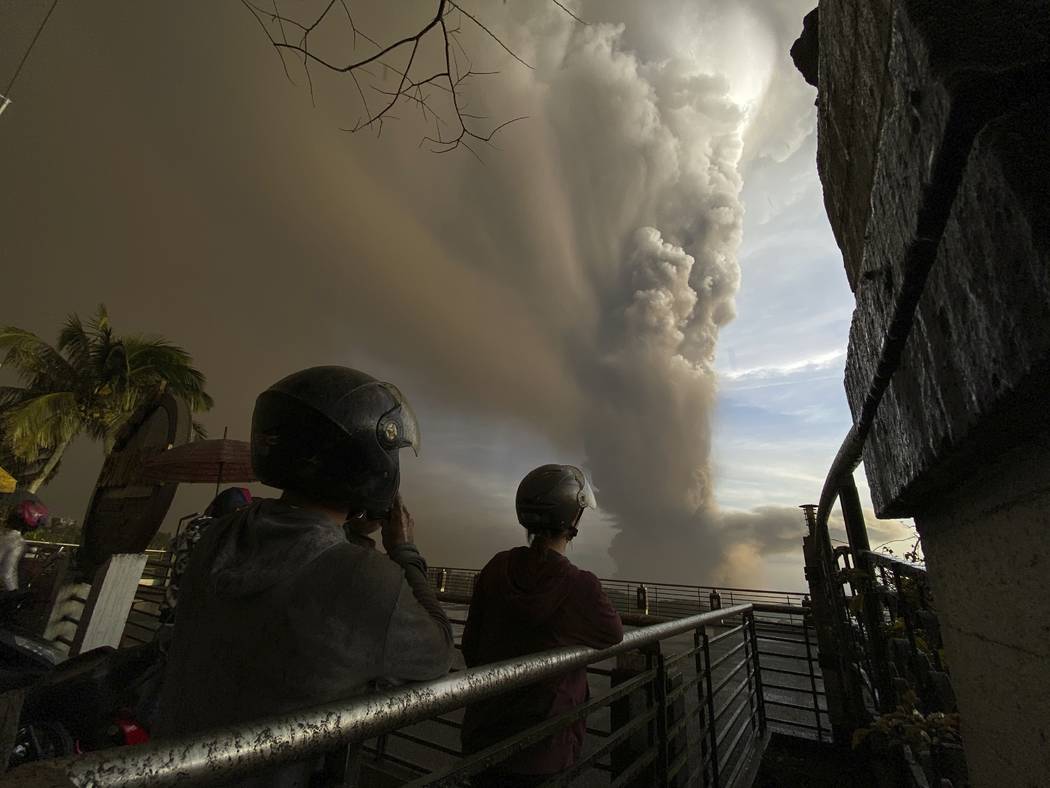 People watch plumes of smoke and ash rise from as Taal Volcano erupts Sunday Jan. 12, 2020, in ...