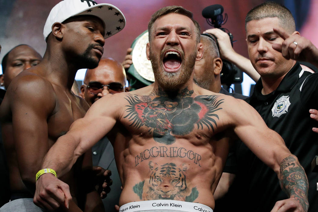 Conor McGregor, center, stands next to Floyd Mayweather Jr., center left, during their weigh-in ...