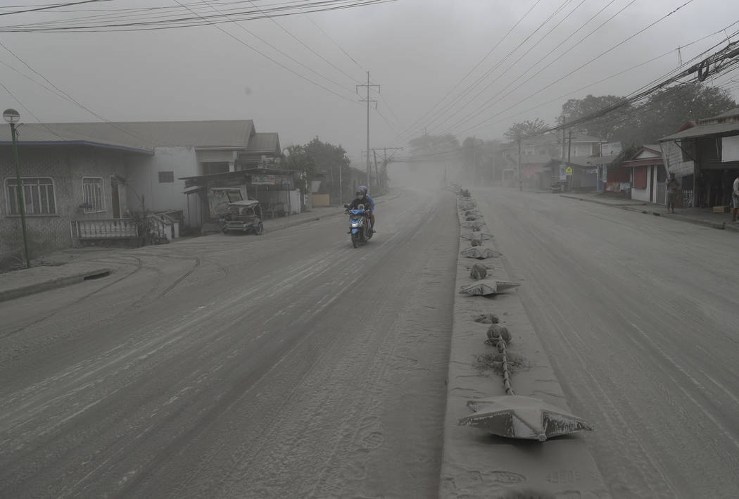 A man negotiates a road covered with ash spewed from Taal Volcano in Lemery, Batangas, southern ...