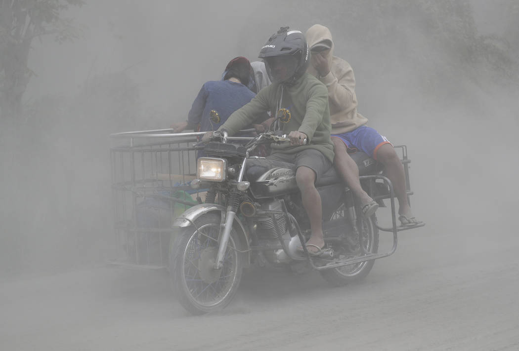 A family rides their motorcycle through clouds of ash as they evacuate to safer grounds as Taal ...
