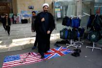 A cleric walks on the U.S. and British flags while leaving a gathering to commemorate the late ...