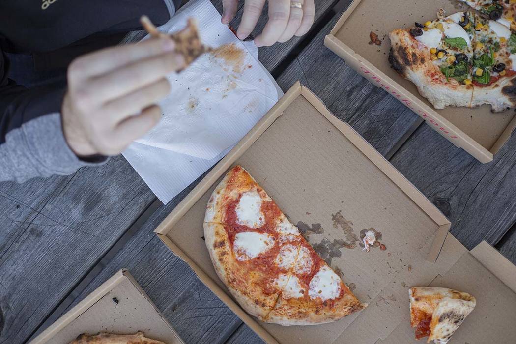 A Custom Pizza Truck costumer eats the Salami Gorgonzola pizza outside of the food truck on Thu ...