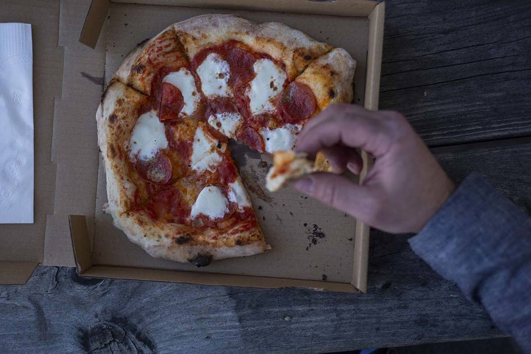 A Custom Pizza Truck costumer eats the Salami Gorgonzola pizza outside of the food truck on Thu ...