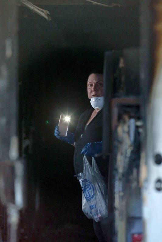 An investigator gathers evidence in the hallway at the front door of the Alpine Motel Apartment ...