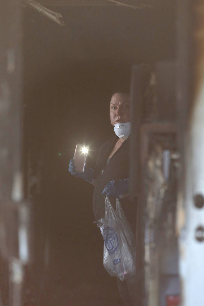 An investigator gathers evidence in the hallway at the front door of the Alpine Motel Apartment ...