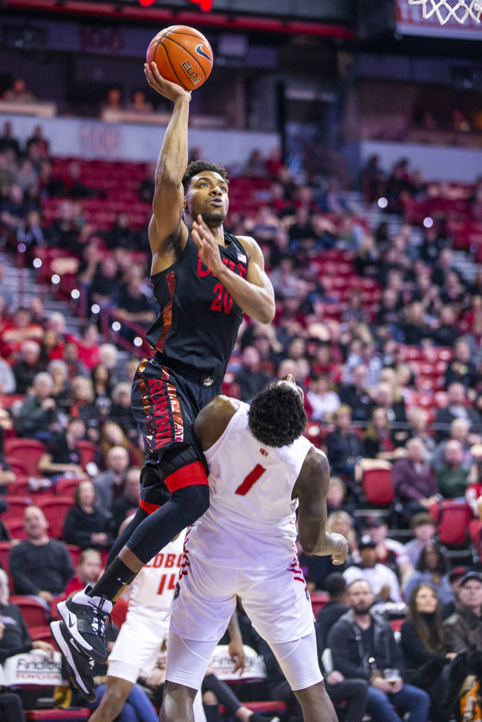 UNLV Rebels forward Nick Blair (20, above) attempts a shot over the top of New Mexico Lobos for ...