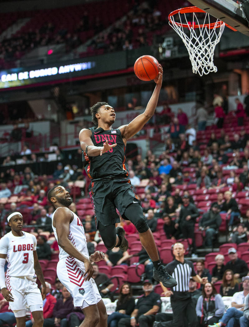 UNLV Rebels guard Bryce Hamilton (13, right) lays in the ball over New Mexico Lobos guard JaQua ...