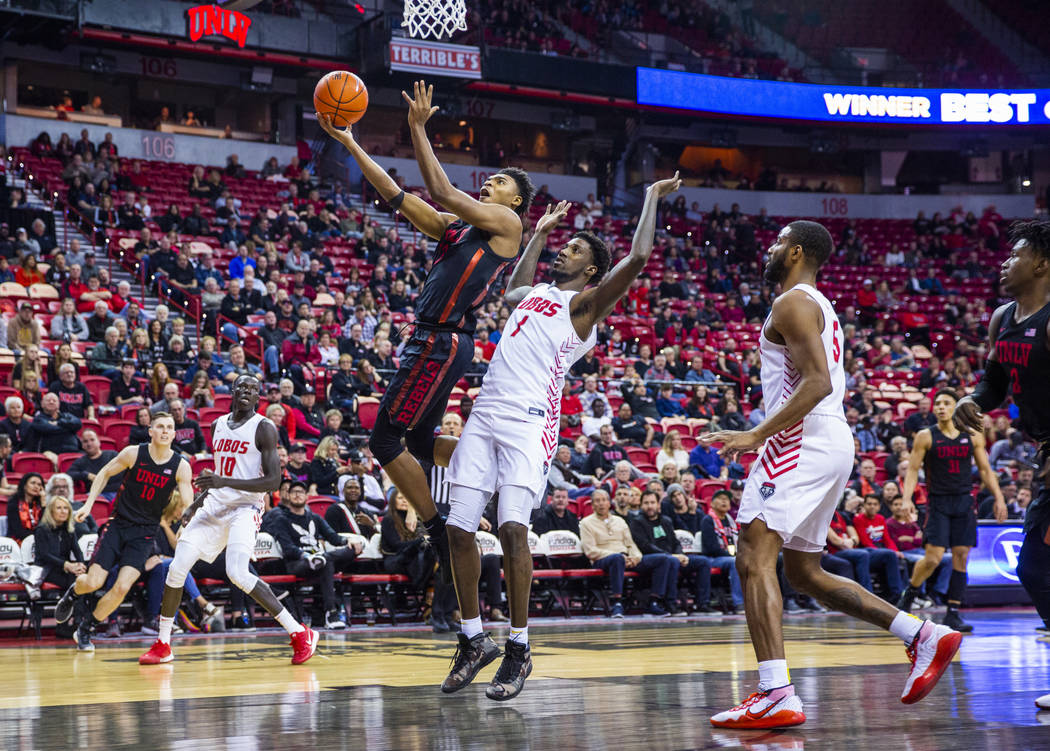 UNLV Rebels guard Bryce Hamilton (13, left) drives past New Mexico Lobos forward Corey Manigaul ...