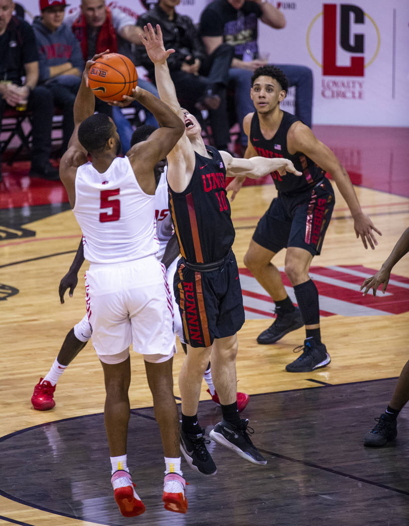 New Mexico Lobos guard JaQuan Lyle (5, left) seats up a shot over the outstretched arm of UNLV ...