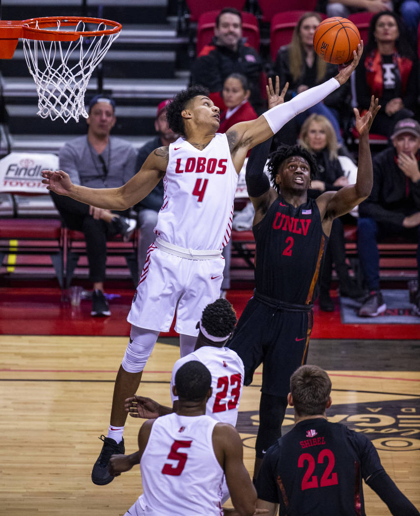 New Mexico Lobos guard Tavian Percy (4, left) extends while leaping to grab a rebound from UNLV ...