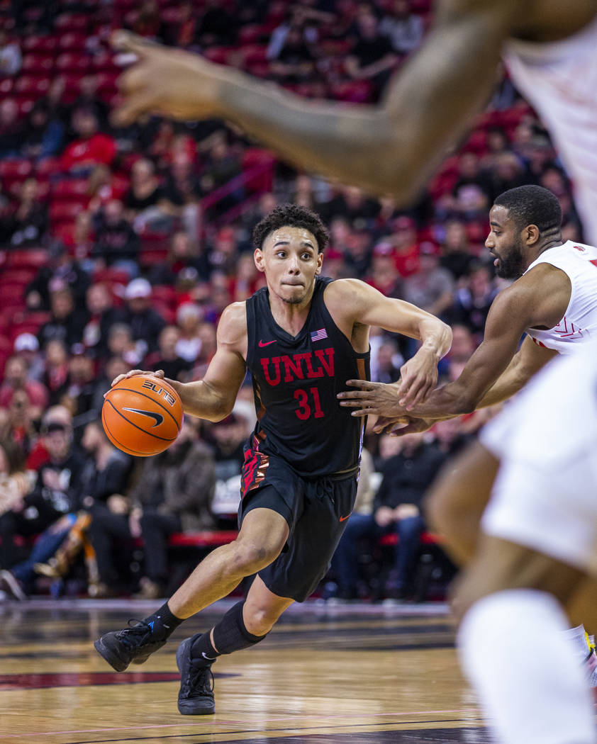 UNLV Rebels guard Marvin Coleman (31, center) drives the lane versus New Mexico Lobos guard JaQ ...