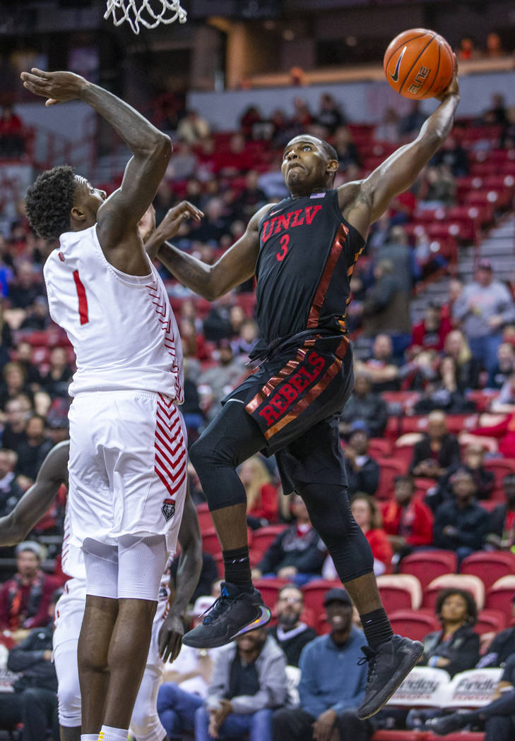UNLV Rebels guard Amauri Hardy (3, right) sets up a big dunk over New Mexico Lobos forward Core ...
