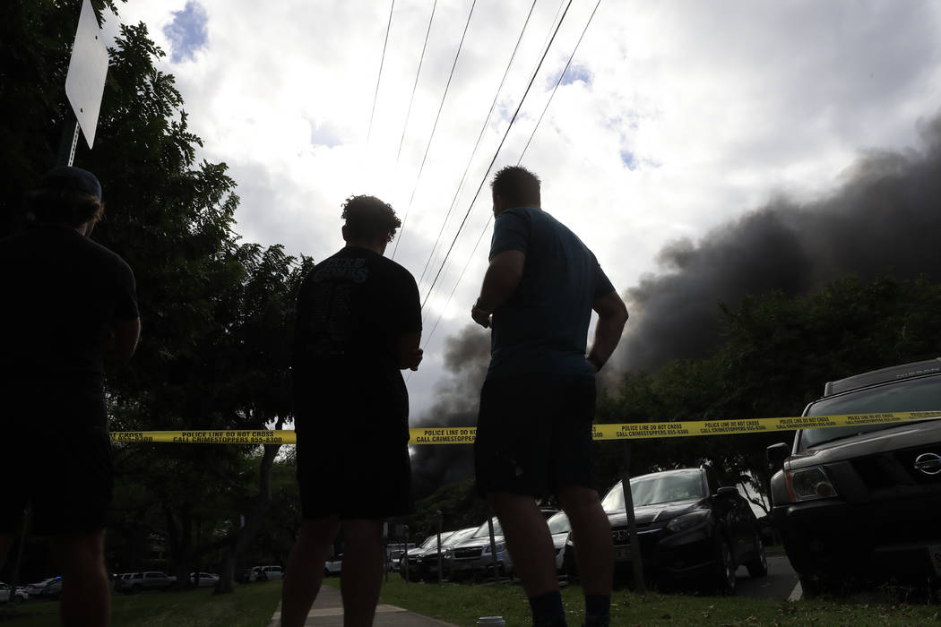 Bystanders watch black smoke billowing from a house fire after a shooting and domestic incident ...