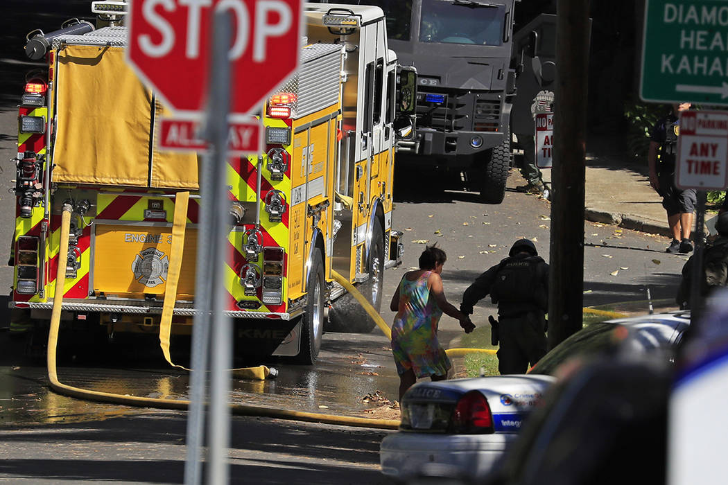 A Honolulu police officer escorts Dolores Sandvold back to her home near the scene of a deadly ...