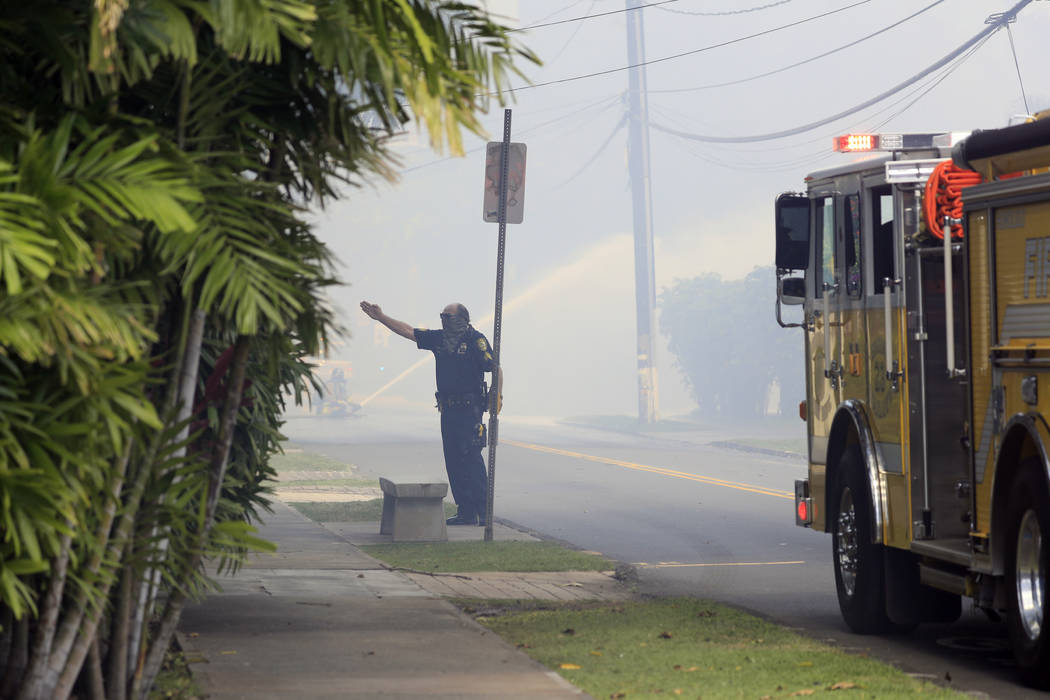 A Honolulu police officer directs traffic near the scene of multiple house fires in the Diamond ...
