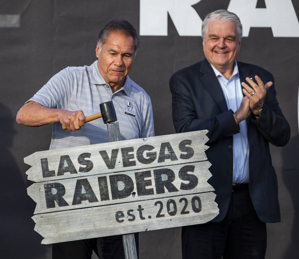 Former Oakland Raiders great Jim Plunkett, left, hammers a ceremonial sign into the ground besi ...